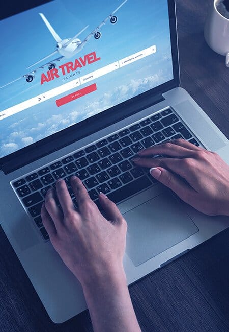 A woman types on her MacBook Pro, she is on an airline website ordering tickets