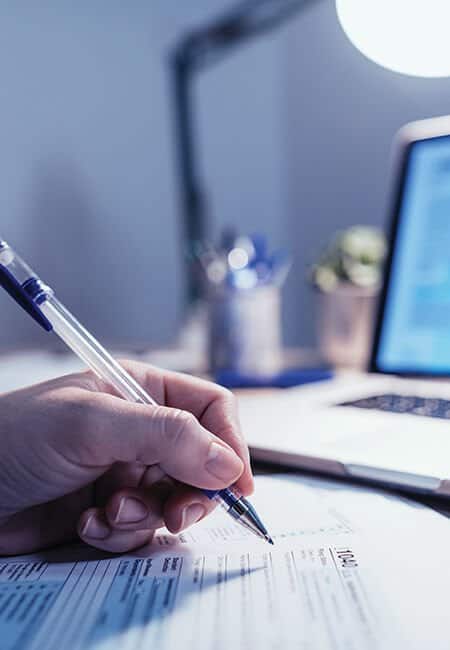 A woman sits at her desk filling out paperwork.
