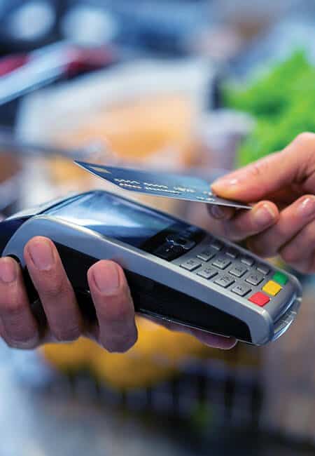 A person pays for their purchase by tapping their wireless credit card chip to the payment kiosk.